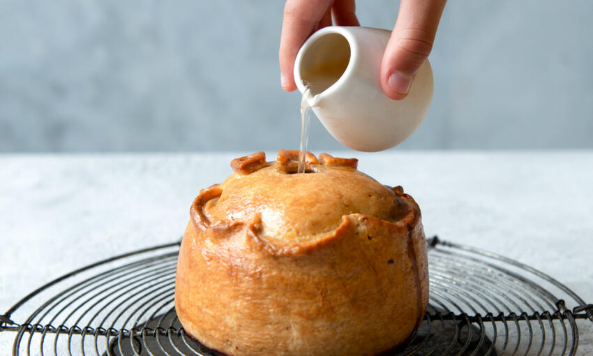 pouring stock jelly into cooked dad pork pie
